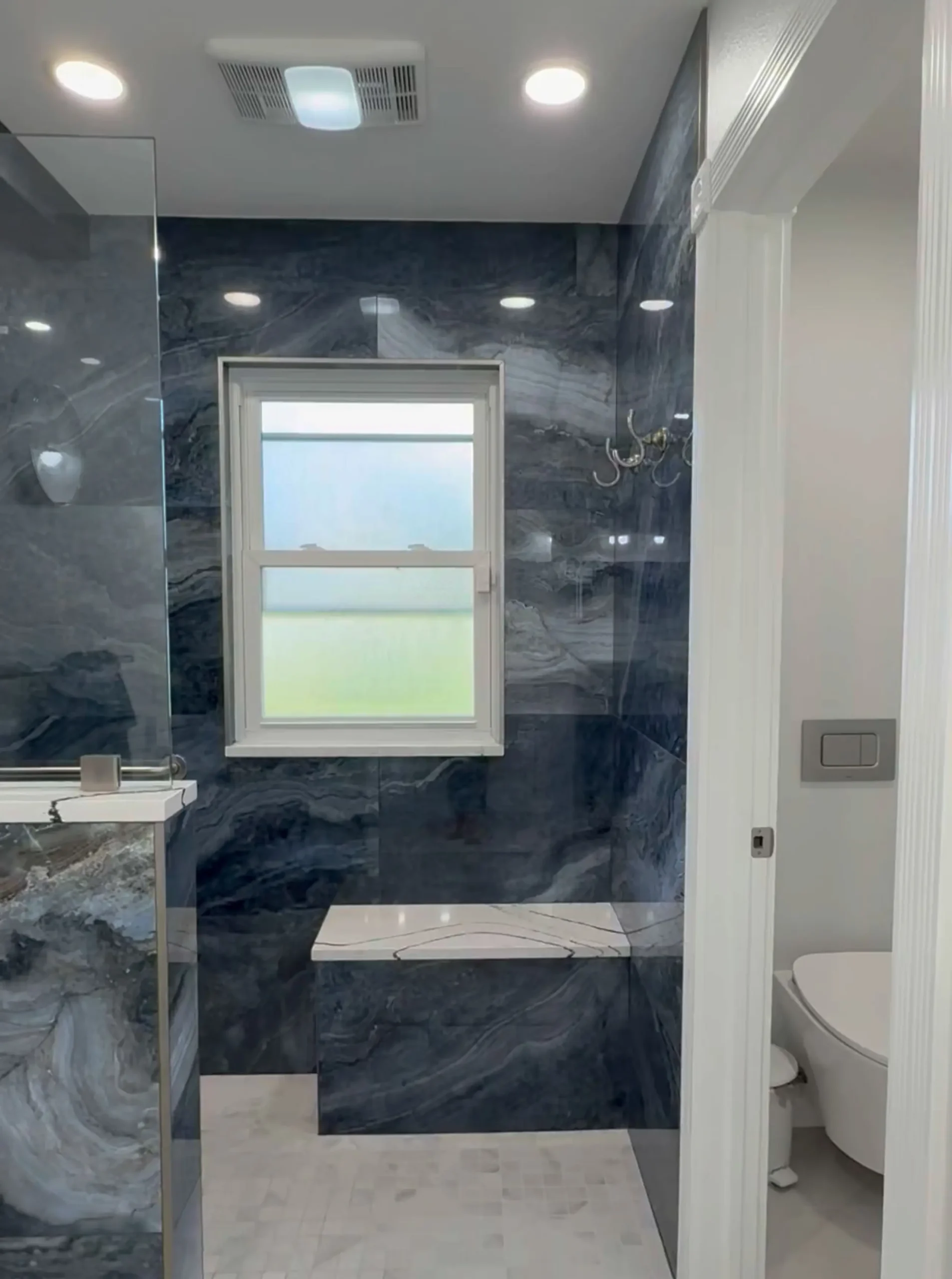 primary walk-in shower with a built-in bench, water closet with a concealed toilet tank