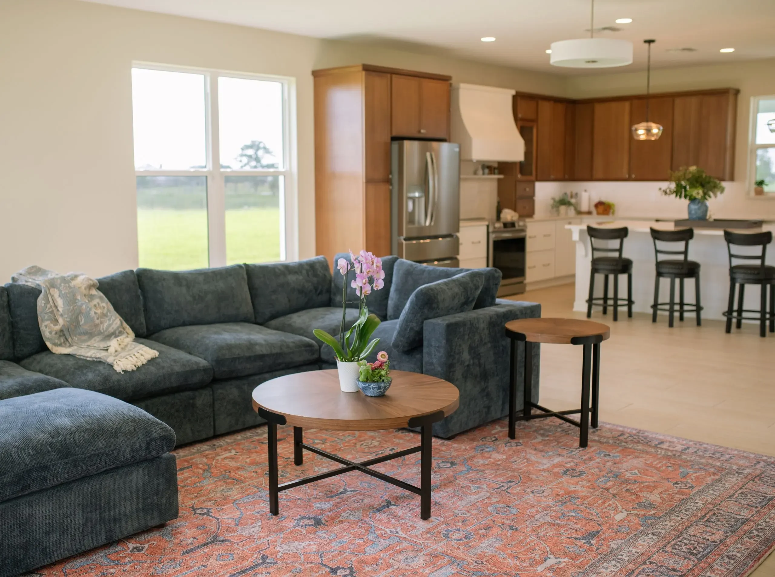 Open-concept living room and kitchen with sectional sofa, wood cabinetry, and large windows