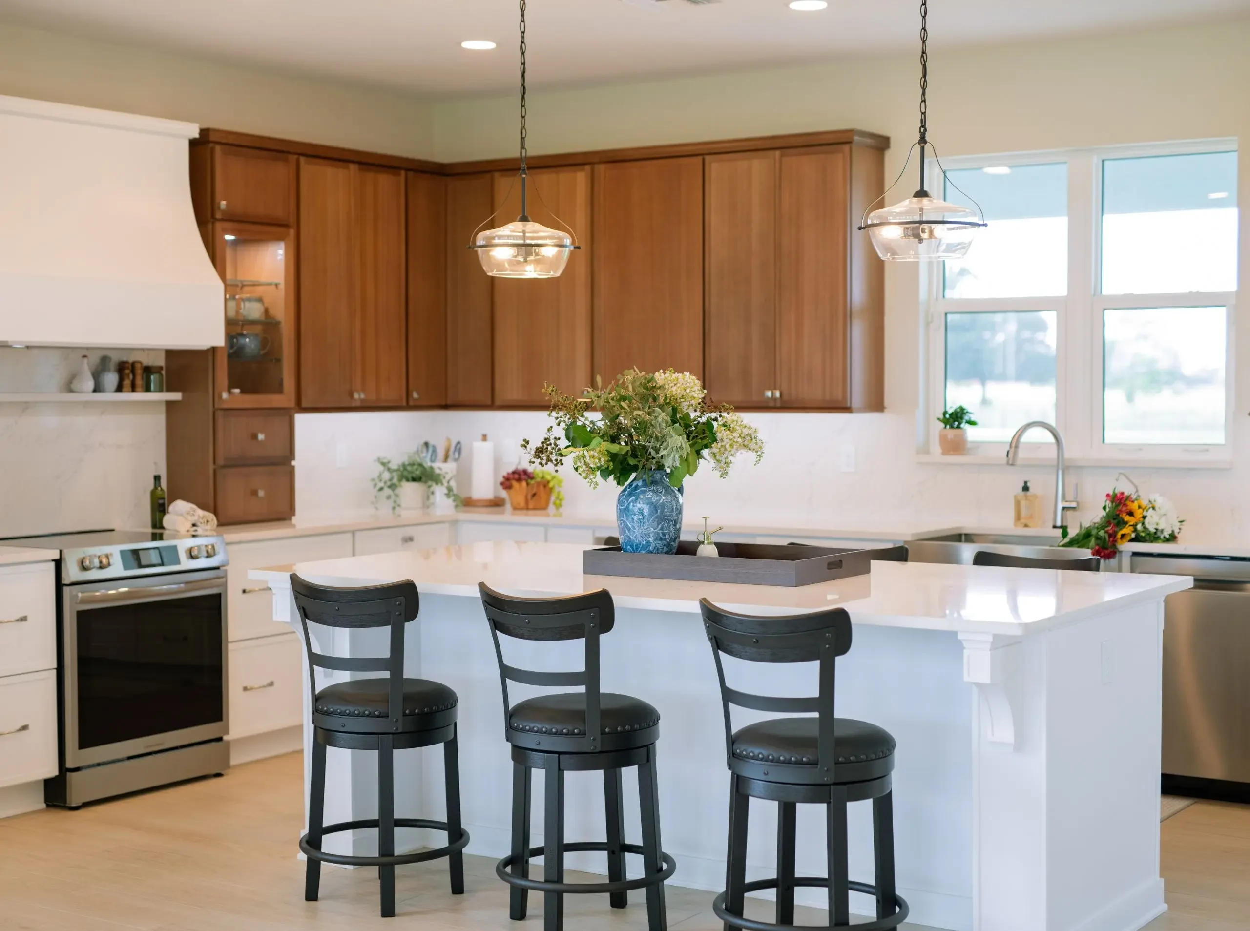 Two-tone kitchen with natural wood upper cabinetry, white lower cabinets, and a large white island with seating