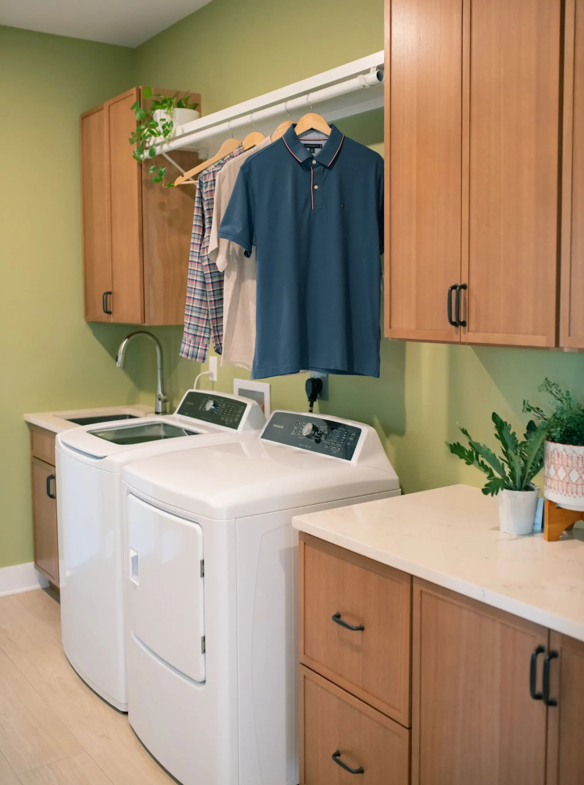 Combined laundry and mudroom with wood cabinetry, utility sink, washer and dryer, and hanging rod